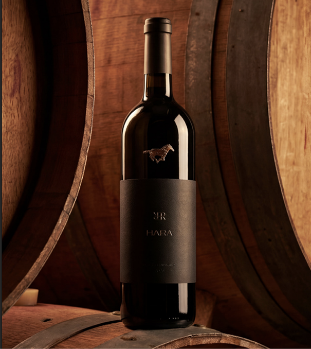 Garrafa do vinho HARA sobre barris de carvalho